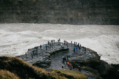 People standing on rock at shore