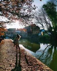 Woman standing by canal during autumn