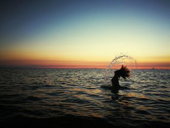 Silhouette woman standing in sea against clear sky