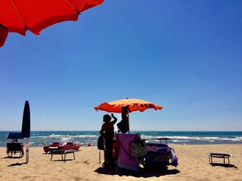 People on beach against clear sky