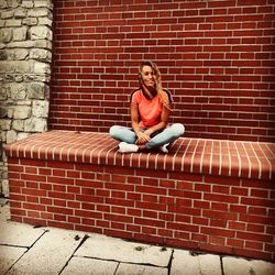 Portrait of man sitting on brick wall