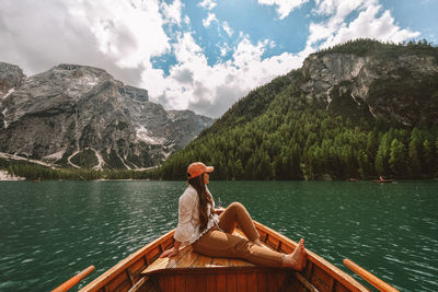 Man sitting by lake against mountains