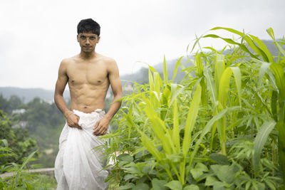 Young indian fit boy, walking on a pathway beside crops in the field. an indian priest walking.