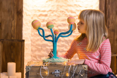 Girl holding knitted christmas decoration at home