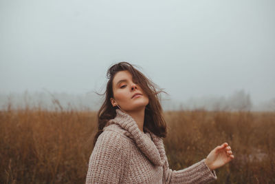 Beautiful woman standing on field against sky during winter