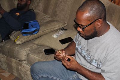 High angle view of man making marijuana joint on sofa at home