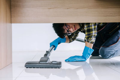 Portrait of smiling man cleaning floor with vacuum cleaner at home