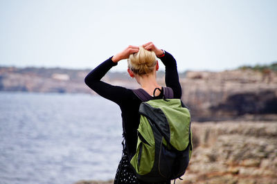 Rear view of woman standing in sea against sky