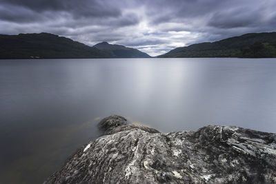 View of rock formation amidst lake by mountain range against clo