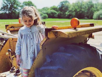 Girl standing on agricultural machinery at farm