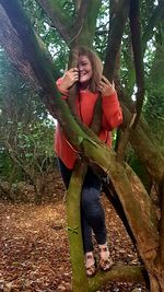 Happy young woman standing on tree trunk