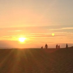 Silhouette people on land against sky during sunset