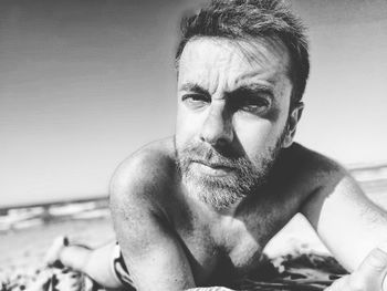 Portrait of shirtless man lying on beach