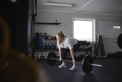 Mid adult woman lifting barbell in gym