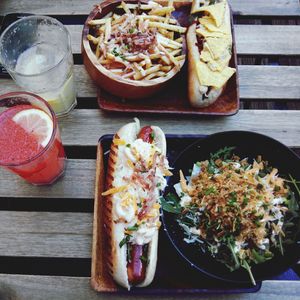 High angle view of hotdogs and salad with french fries on table