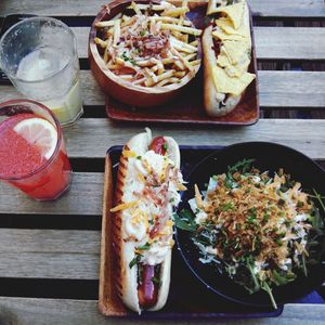 High angle view of hotdogs and salad with french fries on table