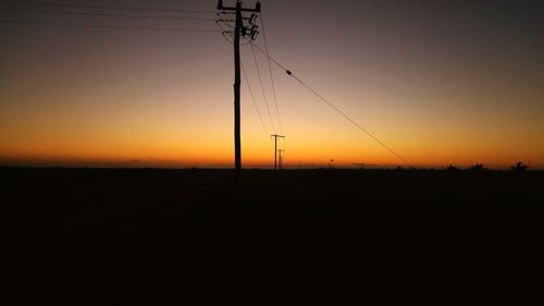 Silhouette of electricity pylon at sunset