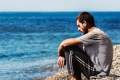 Profile view of man sitting at beach