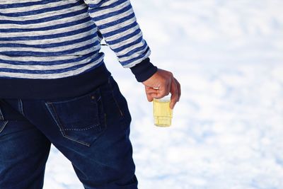 Midsection of man holding drink while standing outdoors