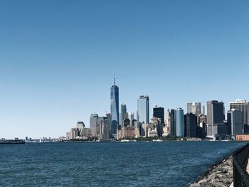 City at waterfront against clear blue sky