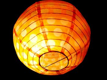 Low angle view of illuminated lantern against orange sky