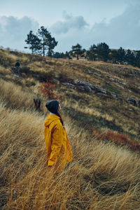 Rear view of woman standing on field against sky