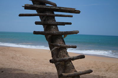 Cross on beach against sky