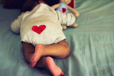 Baby with heart shape on clothing sleeping on bed