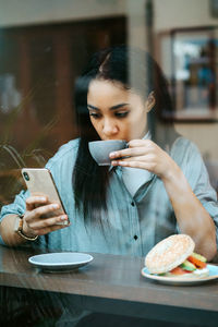 Woman drinking a cup of coffee and using mobile