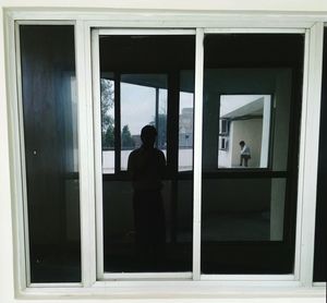 Rear view of man looking through window