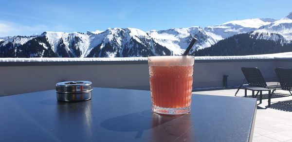 Drink on table against mountains during winter