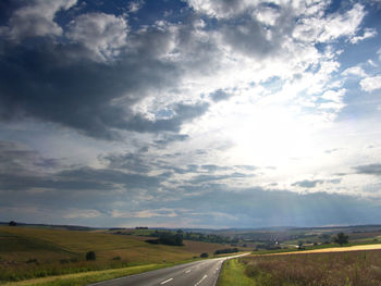 View of country road against cloudy sky