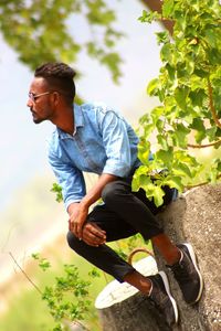 Side view of young man sitting on field