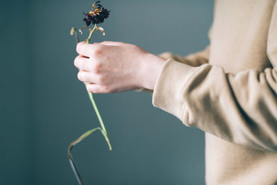 Midsection of man holding dead flower