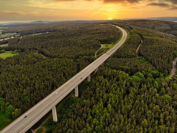 High angle view of road amidst field against sky during sunset