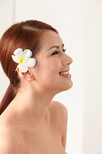 Close-up of woman wearing flower against white background