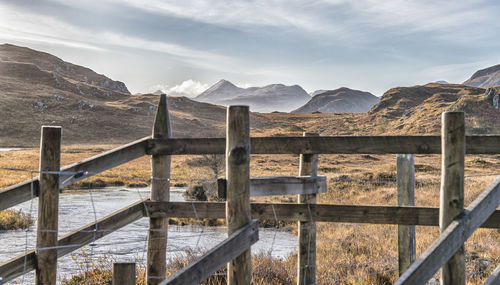 Fence on snowcapped mountains against sky