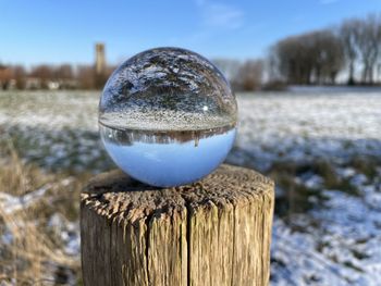 Close-up of crystal ball on wooden post on field during winter