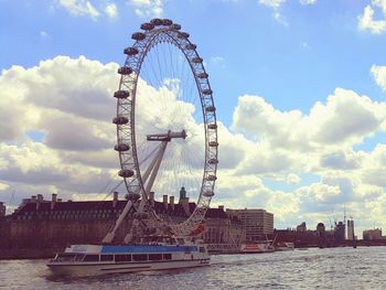 Ferris wheel in city against cloudy sky