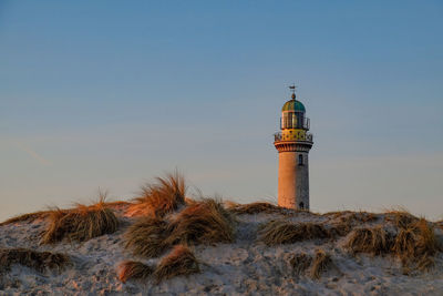 Lighthouse by sea against clear sky