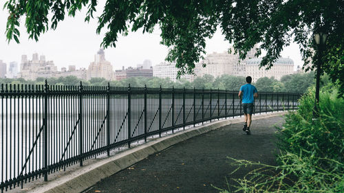 Rear view of man walking by city against sky