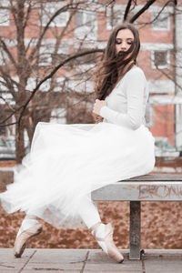 Side view of young woman sitting on bench