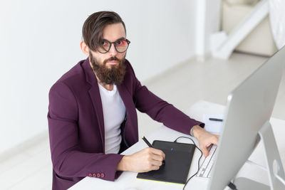 Young man using mobile phone while sitting on table