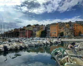 Boats moored in harbor against buildings in city