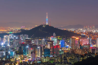 Illuminated buildings in city against sky at night