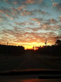 Road against sky during sunset seen through car windshield