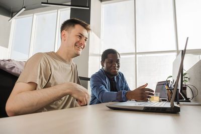 Two smiling positive programmers working in the office of a software development company