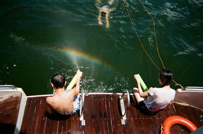 High angle view of friends sitting on boat deck in sea