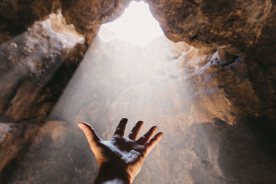 Male hand reaching towards the light. feeling hopeful.