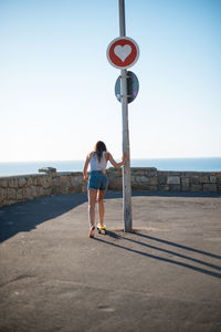 Rear view of woman standing by sea against clear sky